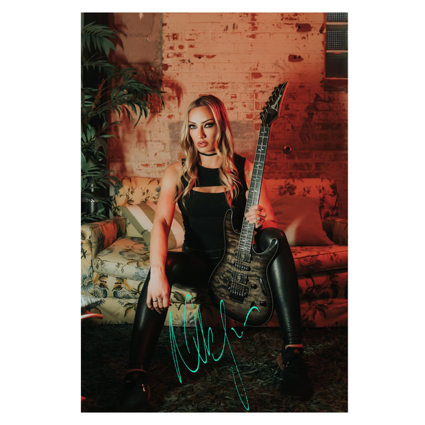 signed 8x10 print titled “Backstage” featuring Nita Strauss seated on a vintage couch in a dimly lit room, holding an guitar with autograph at the bottom